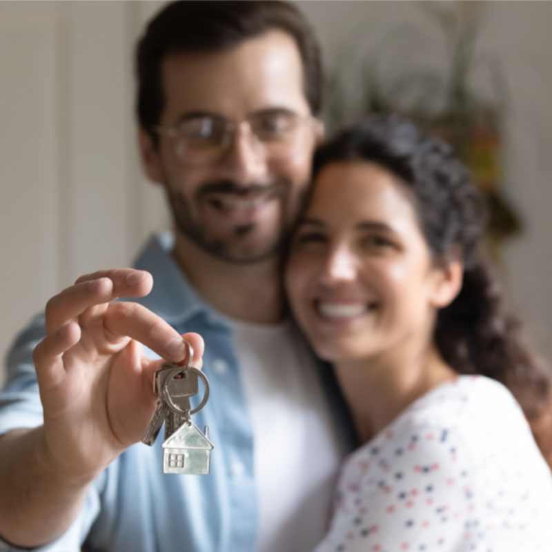 Couple tenant les clefs de leur habitation en souriant